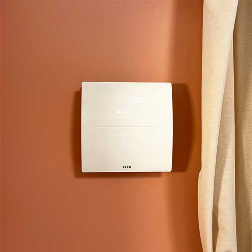 Elta FLUX HR 100 PLUS+ heat recovery unit with remote control, 100mm/4-inch size, mounted on wall in a modern HVAC system